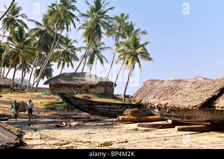 I pescatori portano le loro attrezzature home barche del passato e cottage vicino al villaggio di Varkala Kerala, India Foto Stock