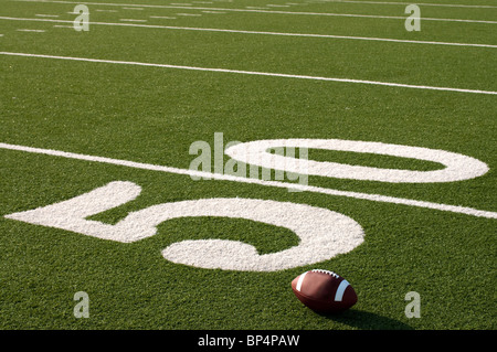 Il football americano sul campo accanto a 50 yard line. Foto Stock