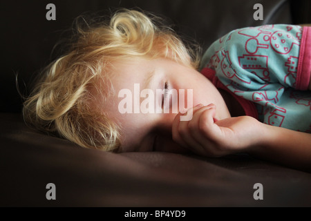 Bambino Toddler ragazza dorme tenendo un pisolino di pomeriggio su un divano succhiare il suo pollice modello rilasciato Foto Stock