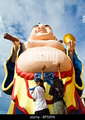 Due giovani donne di toccare la pancia di Kuan Yin statua per fortuna al cinese tempio buddista in Kota Kinabalu, Sabah Malaysia Foto Stock