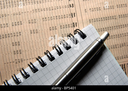 Penna e posa di notebook sul giornale con i dati finanziari. Foto Stock