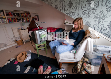 Ragazza adolescente di guardare la televisione e di lavoro sul computer portatile Foto Stock