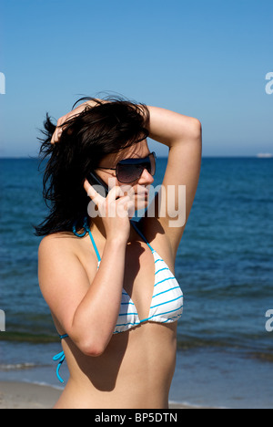 Giovane donna parla al telefono su una spiaggia, Ahrenshoop, Germania Foto Stock