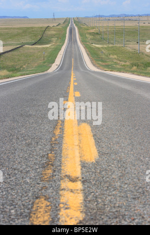 Autostrada dritto nel paesaggio collinare di stato del New Mexico, Anton Chico, STATI UNITI D'AMERICA Foto Stock