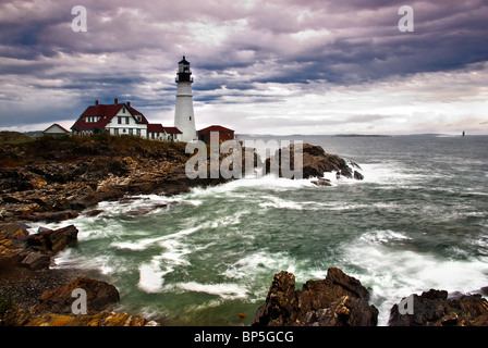 Portland Head Lighthouse si siede sul bordo dell'Oceano Atlantico mentre le onde infrangersi sulla costa rocciosa Foto Stock