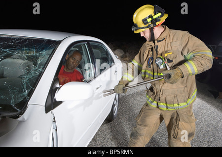 Firefighter salvataggio auto vittima di incidente Foto Stock