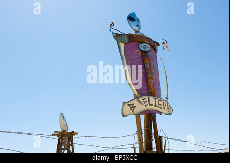 Alien effige con argento UFO nel retro set di massa contro un cielo blu, la parola credere è dipinta sotto l effige. Foto Stock