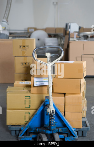 Scatole impilate su carrello in magazzino di distribuzione Foto Stock