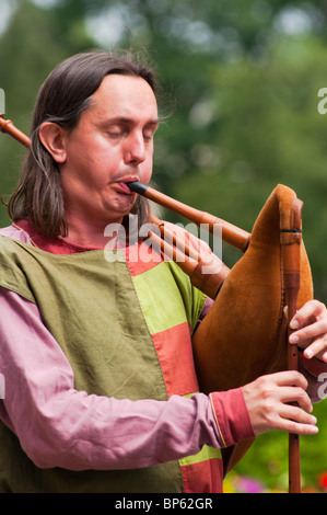 Un uomo giocando un medievale lo strumento musicale costituisce parte di un corteo nuziale come egli passa York Minster nella cattedrale di York. Foto Stock