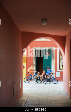 I bambini in bicicletta e persone mangiare in laneways nei giorni festivi Foto Stock