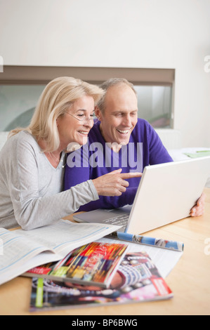Coppia in cerca di un computer portatile e sorridente Foto Stock