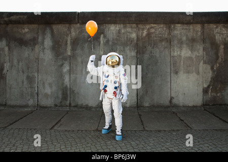 Un astronauta su un marciapiede in città tenendo un palloncino Foto Stock