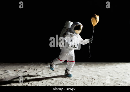 Un astronauta sulla luna tenendo un cuore a forma di palloncino elio Foto Stock