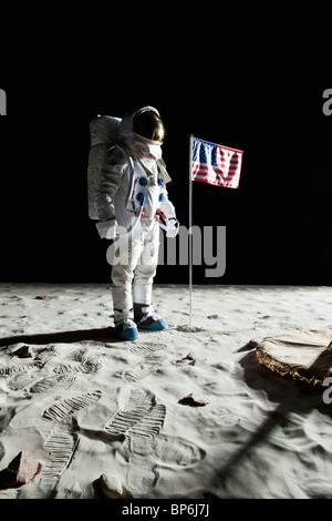 Un astronauta sulla luna in piedi accanto a una bandiera americana Foto Stock