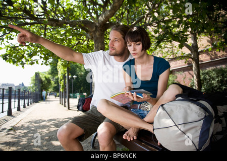 Un giovane uomo di punta, mentre la sua ragazza guarda una mappa con incertezza Foto Stock