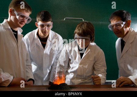 Un insegnante sovrintende agli studenti di fare un esperimento di chimica con la polvere da sparo illuminato Foto Stock