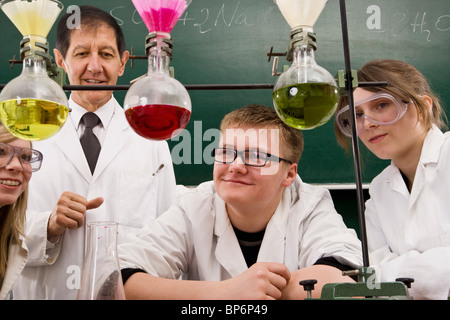 Un insegnante supervisione di due studenti di condurre un esperimento di chimica Foto Stock