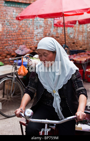 Musulmani donna cinese in sella ad una bicicletta nel villaggio Xizhou, appena fuori Dali, Cina Foto Stock