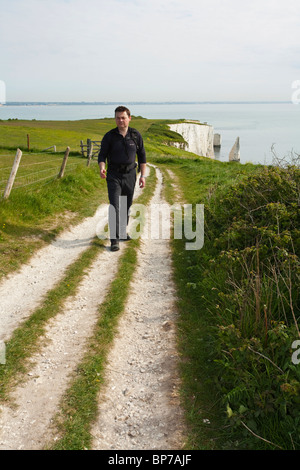 Il camminatore solitario sul sentiero costiero vicino al vecchio Harry rocce vicino a Swanage sull'Isola di Purbeck, Dorset, Regno Unito Foto Stock