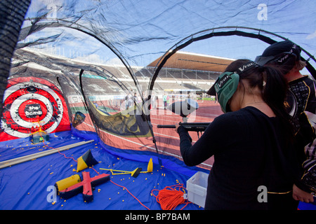 Giovane donna dispositivo di puntamento con una pistola paintball Foto Stock