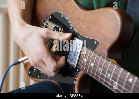 Giovane uomo strimpella corda sulla chitarra Foto Stock