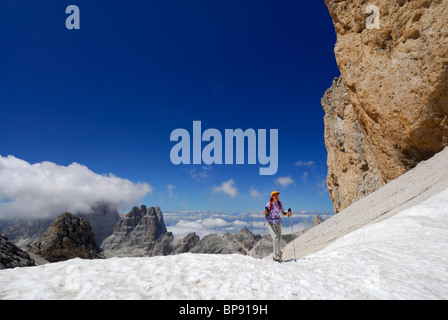 Donna escursionismo su neve a Antermoia Pass, Vajolet torri in background, gruppo del Catinaccio, Dolomiti, Trentino-Alto Adige/ Foto Stock