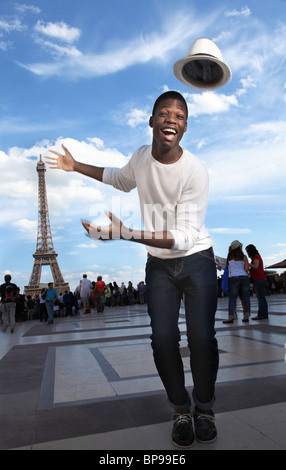 Eccitato giovane con un flying hat, di fronte alla torre eiffel Foto Stock