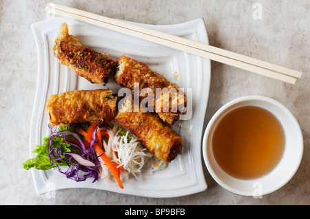 Profondo fritto vietnamita involtini primavera (Cha Gio) sono serviti con verdure trinciato e una salsa di immersione. Foto Stock
