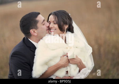 Ontario, Canada; la sposa e lo sposo azienda ogni altra strettamente mentre in piedi in un campo Foto Stock