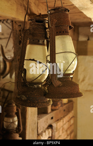 Una coppia di rusty lampade ad olio appesi in una vecchia azienda agricola capannone. Foto Stock