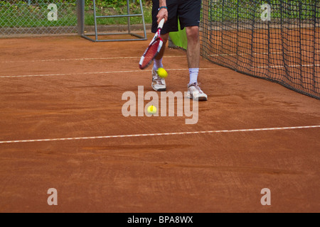 Clay court. Le gambe del giocatore di tennis abile di prelevare la palla con la racchetta. Posizione orizzontale Foto Stock