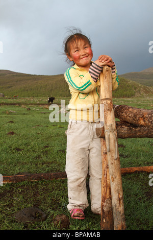 Una ragazza mongola sorrisi per la telecamera come ella si appoggia contro una recinzione Foto Stock