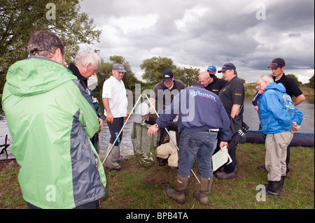 Un gruppo di pescatori si fermò sulle rive del fiume Trent pesatura di una pesca di cattura Foto Stock