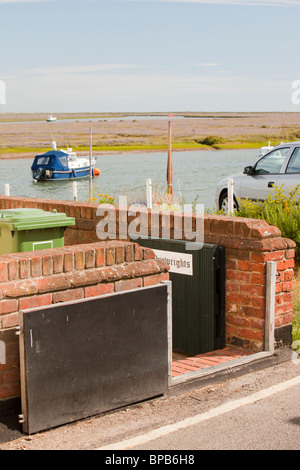 Una casa in pozzetti accanto al mare con un gate di inondazione per la protezione contro la sovracorrente storm inondazioni costiere, Norfolk, Regno Unito. Foto Stock