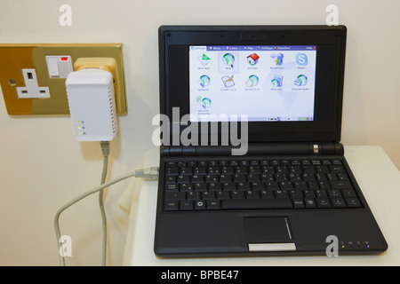 Netbook porta ethernet collegata al HomePlug nella presa elettrica per Internet a banda larga di andare online utilizzando il cablaggio elettrico Foto Stock