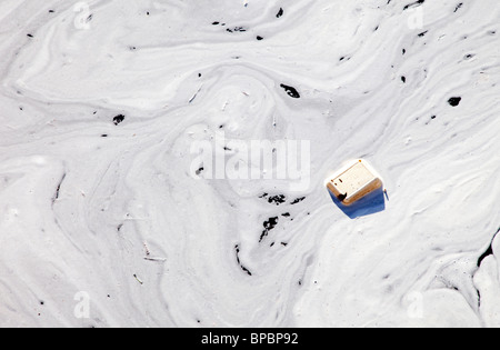 Lo strato di schiuma e di rifiuti che galleggia sulla superficie dell'acqua Foto Stock