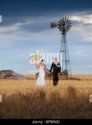 Tre colline, Alberta, Canada; la sposa e lo sposo camminare su terreni agricoli Foto Stock