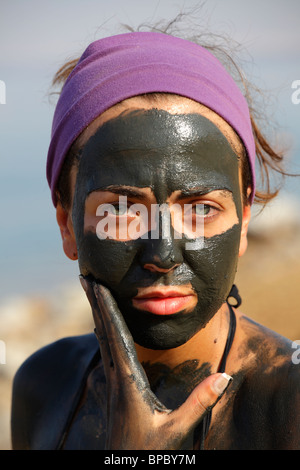 Ragazza giovane nero facendo terapia del fango del Mar Morto, Giordania Foto Stock