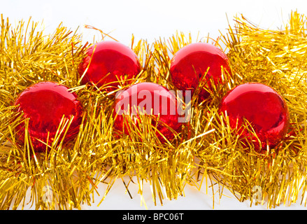 Cinque rosso baubles di natale in appoggio su un nido di oro tinsel isolato su bianco Foto Stock