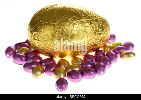 Grandi e piccole di lamina di oro avvolto uova di pasqua di cioccolato su bianco Foto Stock