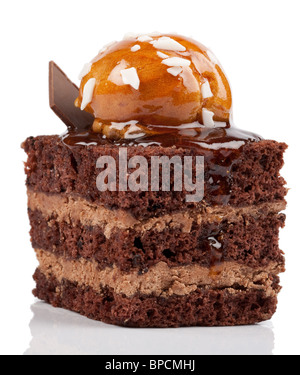 Primo piano di una fetta quadrata di torta al cioccolato a strati, con tre strati di spugna di cioccolato umida separati da due strati di ripieno di crema al cioccolato. La parte superiore è ricoperta da un caramello lucido Foto Stock