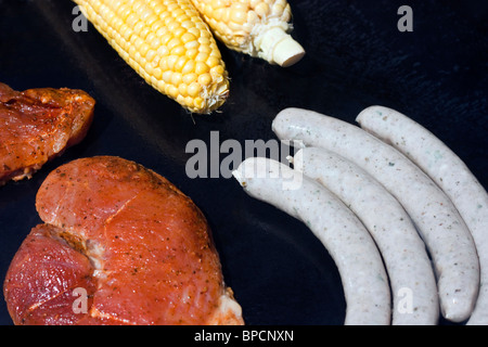 La carne cruda, salsiccia e mais sul grill a gas Foto Stock