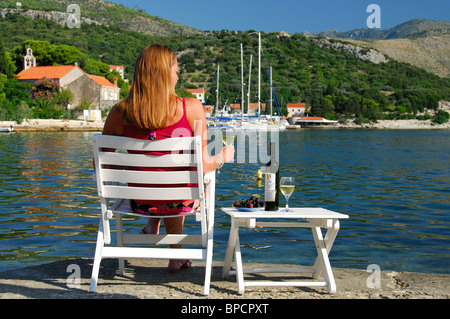 ZATON, vicino a Dubrovnik, Croazia. Una donna in vacanza a bere vino croato e affacciato sulla baia di Zaton. Foto Stock