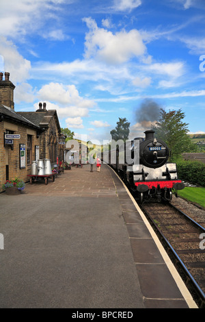 Treno a vapore che arrivano a Oakworth stazione ferroviaria, Keighley e Worth Valley Railway, West Yorkshire, Inghilterra, Regno Unito. Foto Stock