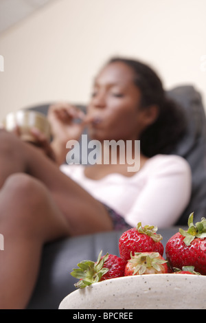 Una donna godendo le fragole ottenendo al contempo una pedicure Foto Stock