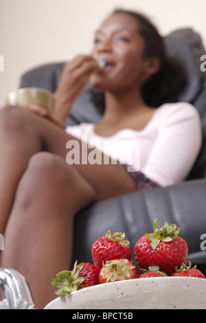 Una donna godendo le fragole ottenendo al contempo una pedicure Foto Stock