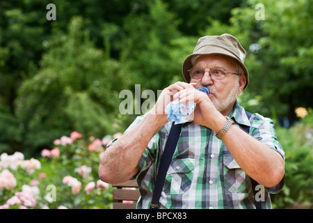 Uomo senior di bere acqua in bottiglia Foto Stock
