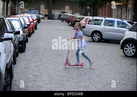 Bambina di otto anni con lo scooter in una strada residenziale a Duesseldorf in Germania. Foto Stock