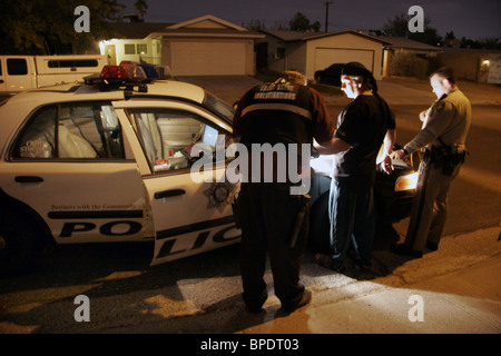 Un sospetto viene arrestato dalla polizia e controllato per prove forensi sulla scena di un assalto a Las Vegas, Nevada, STATI UNITI D'AMERICA Foto Stock