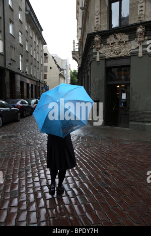Una donna con un ombrello a piedi un edificio stile Art Nouveau nel centro storico di Riga. Lettonia Foto Stock